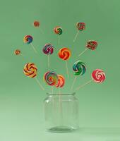 Colorful lollipops coming out of jar against pastel green background. Creative candy concept. Minimal lollipop idea. photo