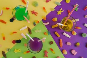 Colorful party cocktails and sweet gummy candies on yellow, green and violet background. Flat lay summer party concept. photo