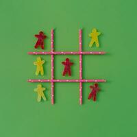 Tic-tac-toe,  noughts and crosses or Xs and Os game made with gummy candies and straws on pastel green background. Funny creative idea. Minimal layout. photo