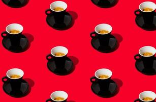 Trendy pattern made of black cup of coffee on red background. Creative coffee concept. Minimal espresso pattern idea. Coffee aesthetic. photo