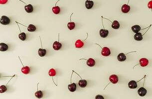 Fruit pattern made of red cherries on pastel cream background. Minimal cherry fruit layout. Creative nature summer pattern concept. Flat lay summer food idea. photo