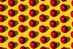 Trendy fruit pattern made of red apples on light yellow background. Minimal concept. photo