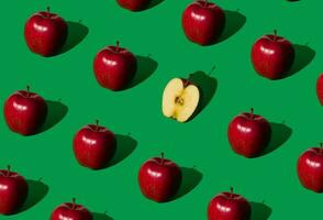 Be different. Trendy fruit pattern made of red apples on bold green background. Nature creative concept. Minimal layout. photo