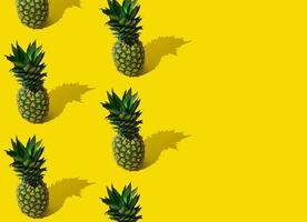 Fresh tropical summer fruit pattern made of pineapple on light yellow background with copy space. Trendy minimal ananas pattern layout. Natural exotic summer food concept. Pineapple aesthetic. photo