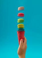 Pink waffle ice cream cone with colorful macarons on bright blue background. Minimal food concept. Sweet creative idea. Yummy macaron cookies and ice cream layout. photo