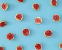 Trendy fruit pattern made of fresh sliced figs on light pastel blue background. Minimal healthy fruit composition. Nature yummy food concept. Flat lay figs pattern background idea. photo