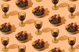 Creative autumn pattern made with fallen laeves, berries, pumpkins, pinecones and glasses of red wine on pastel orange background. Minimal nature seasonal concept. Flat lay idea. Autumn aesthetic. photo