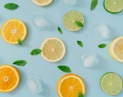 Creative summer background composition with orange, lemon and lime slices, green mint leaves and ice cubes. Minimal top down lemonade drink concept. Citrus fruit aesthetic. Flat lay background. photo