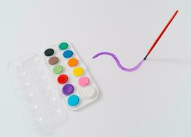 Trendy school layout made of watercolor paint set with brush on white background. Minimal back to school concept. Creative flying brush idea. photo