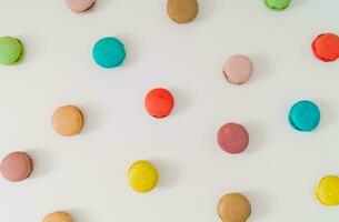 Creative colorful pattern made of various macarons on white background. Minimal sweet food concept. Trendy macaron cookies pattern background. Yummy flat lay idea. photo