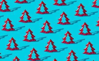 Minimal composition pattern background of red Christmas trees on light blue. New Year or Christmas concept. Trendy winter holidays pattern background idea. photo