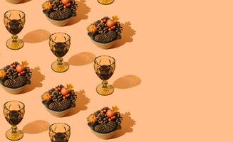 Creative autumn pattern made with fallen laeves, berries, pumpkins, pinecones and glasses of red wine on pastel orange background. Minimal nature seasonal concept. Flat lay idea. Autumn aesthetic. photo