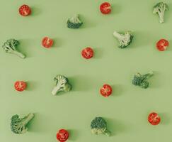 de moda comida modelo hecho de brócoli y Cereza Tomates en pastel verde antecedentes. creativo vegetal modelo idea. plano laico brócoli y Cereza Tomates composición. vegetal estético. foto
