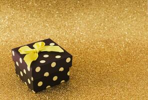 Closeup view minimal composition of Christmas gift box on golden backdrop. New Year present concept background. Trendy gift box idea. Luxury layout with copy space. photo