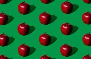 Trendy fruit pattern made of red apples on bold green background. Nature creative concept. Minimal layout. photo