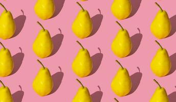 Trendy fruit pattern made of yellow pears on light pastel pink background. Minimal layout. Nature summer concept. photo