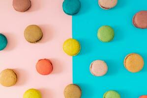 Creative colorful pattern made of various macarons on pastel pink and blue background. Minimal sweet food concept. Trendy macaron cookies pattern background. Yummy flat lay idea. photo