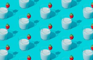 Creative pattern composition made of milk drink with strawberry taste in glass cup on light blue background. Minimal smoothie or milkshake concept. Healthy food for breakfast and snack idea. photo