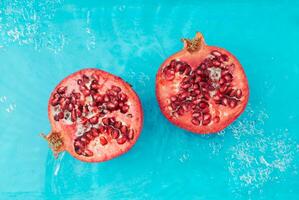 Trendy scene with fresh pomegranate in water. Minimal nature background concept. Creative healthy fruit layout. Pomegranate aesthetic. Flat lay, top of view. photo