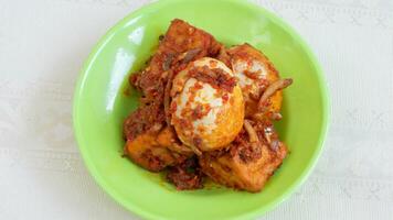 Balado egg sauce, chili sauce filled with eggs, anchovies, and tofu. Served in a bowl on a gray background. Selected focus. photo