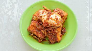 Balado egg sauce, chili sauce filled with eggs, anchovies, and tofu. Served in a bowl on a gray background. Selected focus. photo