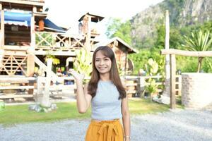 Happy Asian female tourist next to accommodation building during sunset photo