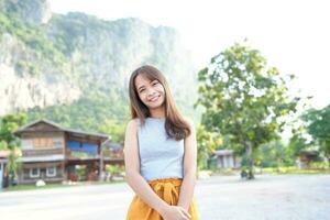 Happy Asian female tourist next to accommodation building during sunset photo