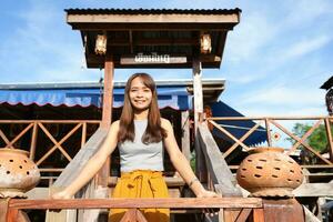 Happy Asian female tourist next to accommodation building during sunset photo