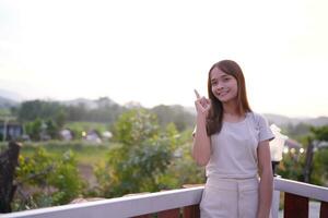 Happy Asian female tourist taking photos on the roof of her accommodation during sunset.