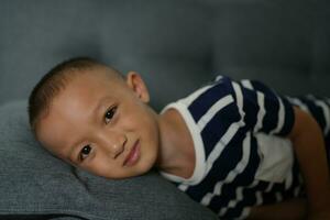 Happy smiling Asian boy on the sofa inside the house. photo