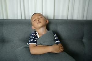 asiático chico dormido en el sofá dentro el casa foto