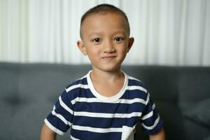 Happy smiling Asian boy on the sofa inside the house. photo