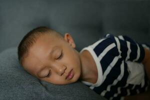 Asian boy sleeping on the sofa inside the house photo