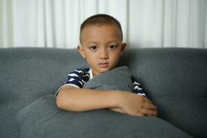 Happy smiling Asian boy on the sofa inside the house. photo