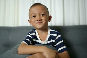 Happy smiling Asian boy on the sofa inside the house. photo