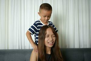 Asian boy massaging mother's shoulders and arms photo