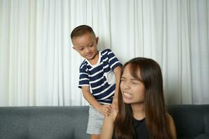 Asian boy massaging mother's shoulders and arms photo