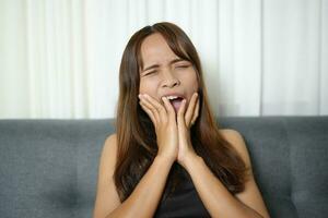 asiático mujer tiene dolor de muelas desde diente decaer foto