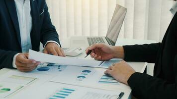Two business partnership coworkers analysis cost work progress and gesturing with discussing a financial planning graph and company financial during a budget meeting in office room. photo
