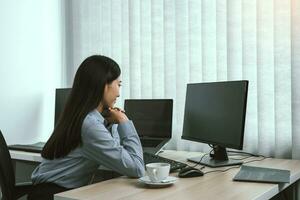 Asian woman software developers sitting in front of computers looking at computer codes on the screen. photo