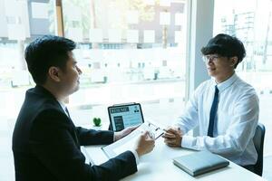 Asian young adult sitting at desk across from manager being interviewed job interview in business room. photo