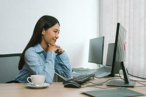 Asian woman software developers sitting in front of computers looking at computer codes on the screen. photo