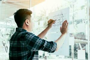 Interior designer or architect reviewing blueprints and holding pencil drawing on desk at home office. photo