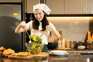 ama de casa asiática preparando verduras frescas para hacer ensalada en el mostrador de la cocina de casa. foto