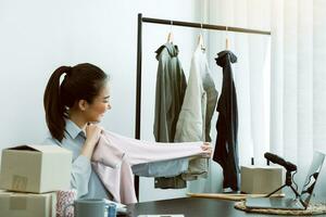 Young asian entrepreneurs are picking up shirts to compare proportions for customers to view them online. photo