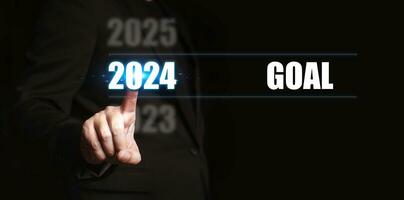 New year 2024 with goal. Businessman pointing to the numbers of the year to set goals for the coming year. photo