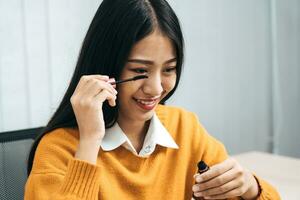 Young asian woman vlogging about cosmetics skin care items products on table with her video camera and demonstrates product use and reviews for her online blog channel. photo