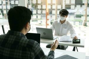 Asian colleague works while wearing a mask in the office during COVID-19. photo