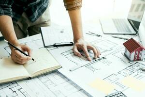 Interior designer or architect reviewing blueprints and holding pencil drawing on desk at home office. photo