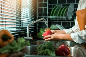 Asian hands woman washing vegetables bell pepper and preparation healthy food in kitchen. photo